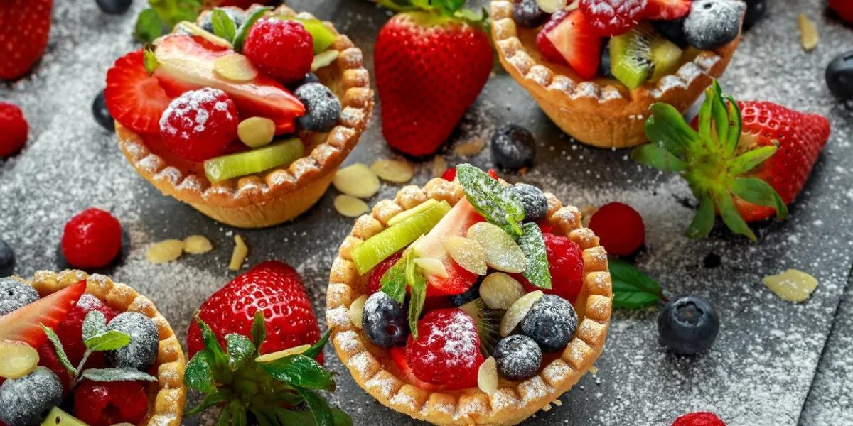 berry tartlets with blueberries, raspberries, kiwi, strawberries, almond flakes in icing sugar