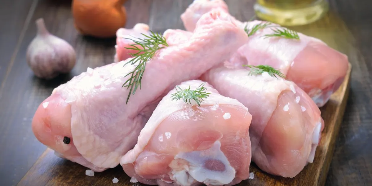 pilons de poulet cru et épices sur une planche à découper en bois