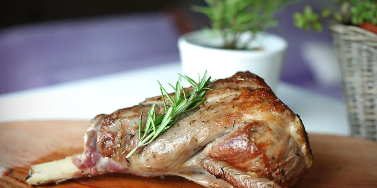 gigot d'agneau rôti au romarin sur la planche à découper dans la cuisine domestique gigot d'agneau rôti au romarin sur la planche à découper dans la cuisine domestique