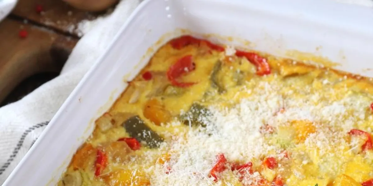 vegetable clafoutis with red bell pepper and zucchini in ceramic bakeware, grated parmesan cheese garnish french cuisine, rustic style