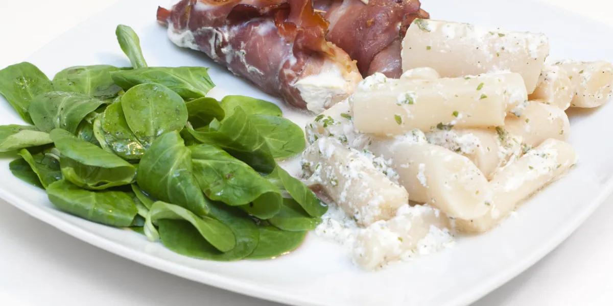 saumon fumé dans une couche de jambon fumé, servi avec de la racine noire et de la laitue d'agneau