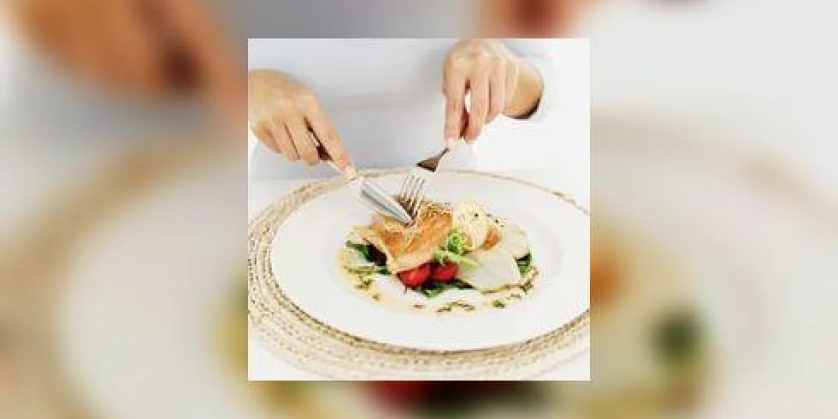 personne utilisant une fourchette et un couteau sur une assiette de saumon grillé