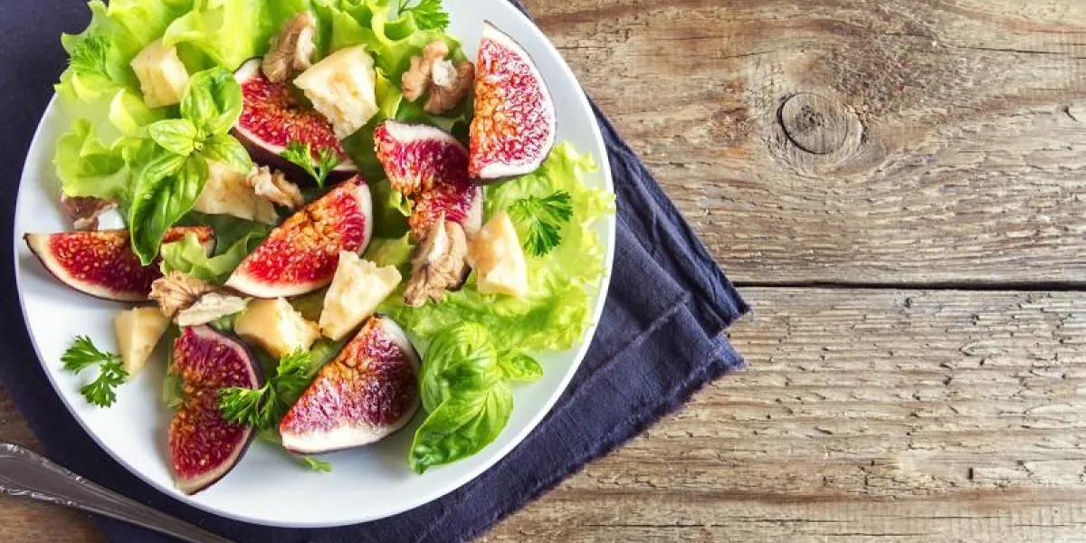 fig fruits, cheese and walnuts salad on plate close up - homemade healthy vegetarian or diet salad