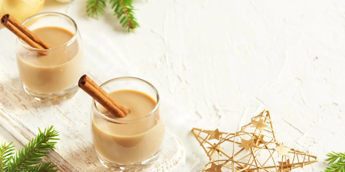 lait de poule avec des bâtons de cannelle, décoration de noël et ornements sur fond blanc - boisson festive de noël alcoolisée maison, cocktail lait de poule avec des bâtons de cannelle, décoration de noël et ornements sur fond blanc - boisson festive de noël alcoolisée maison, cocktail