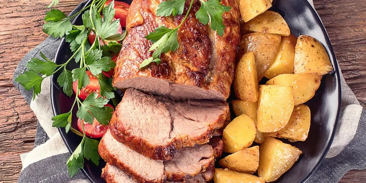roast pork with herbs and vegetables on rustic wooden table roast pork with herbs and vegetables on rustic wooden table